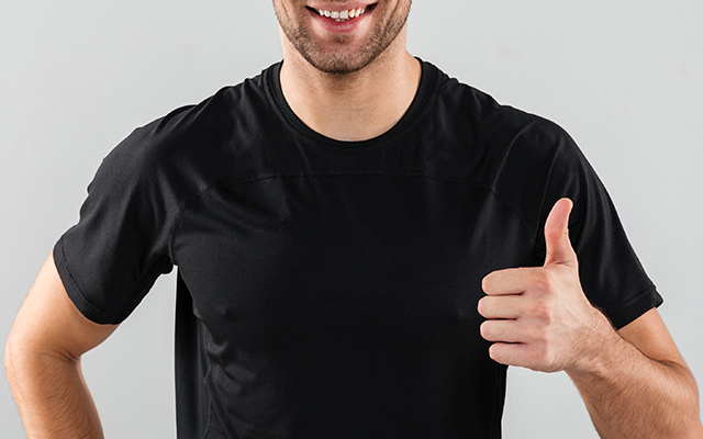 Hombre con camiseta negra levanta el dedo pulgar mientras sonríe